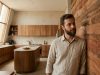 Arsitek Leandro Neves merenungkan dinding taipa de mão yang bertekstur tanah liat di dalam loft minimalis modernnya.