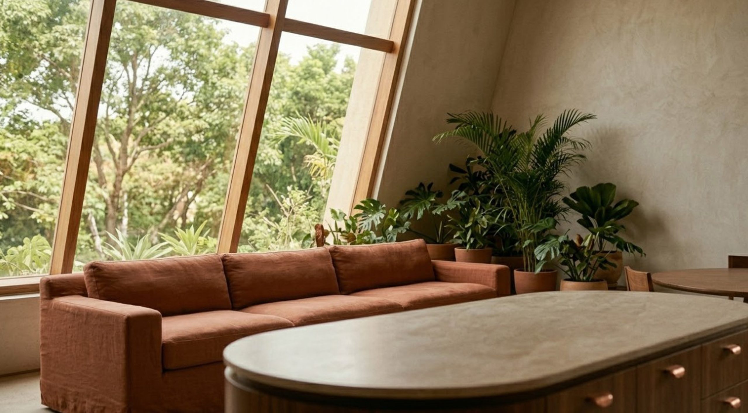 Taman indoor mini di belakang sofa menciptakan suasana tenang dan menyatukan interior dengan pemandangan hijau di luar rumah.