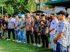 Camat Halongonan Timur memegang mikrofon dan memberikan sambutan kepada pejabat desa di bawah tenda panggung.