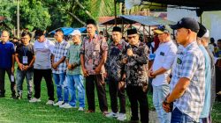 Camat Halongonan Timur memegang mikrofon dan memberikan sambutan kepada pejabat desa di bawah tenda panggung.