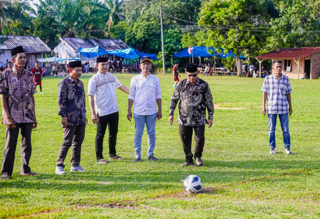 Camat Halongonan Timur menendang bola sepak putih dan biru untuk pembukaan Desa Rondaman Cup I.