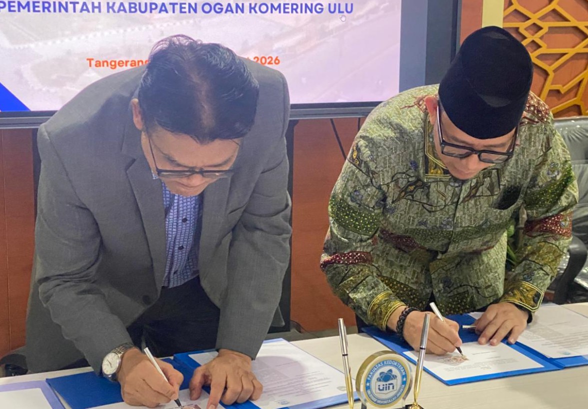 Rektor UIN Syarif Hidayatullah Jakarta (jas abu-abu, kemeja biru muda, kacamata) dan Bupati OKU H Teddy Meilwansyah (peci hitam, kemeja batik hijau, kacamata), sedang menandatangani dokumen secara bersamaan.