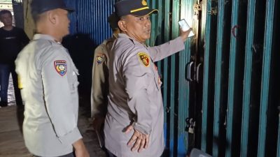 Proses pemasangan garis polisi berwarna kuning oleh aparat di depan deretan kios Pasar Atas OKU.