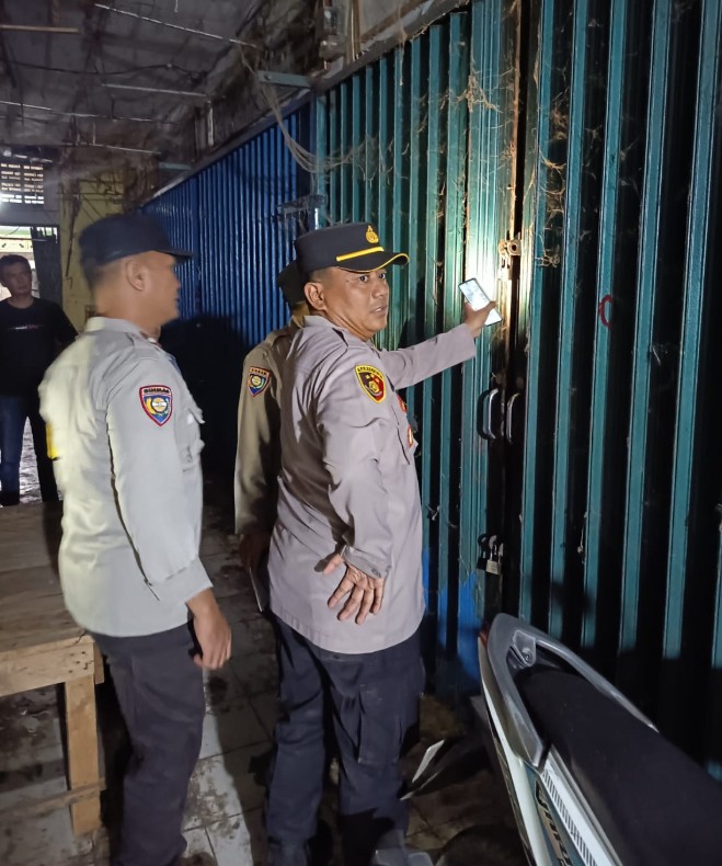 Proses pemasangan garis polisi berwarna kuning oleh aparat di depan deretan kios Pasar Atas OKU.