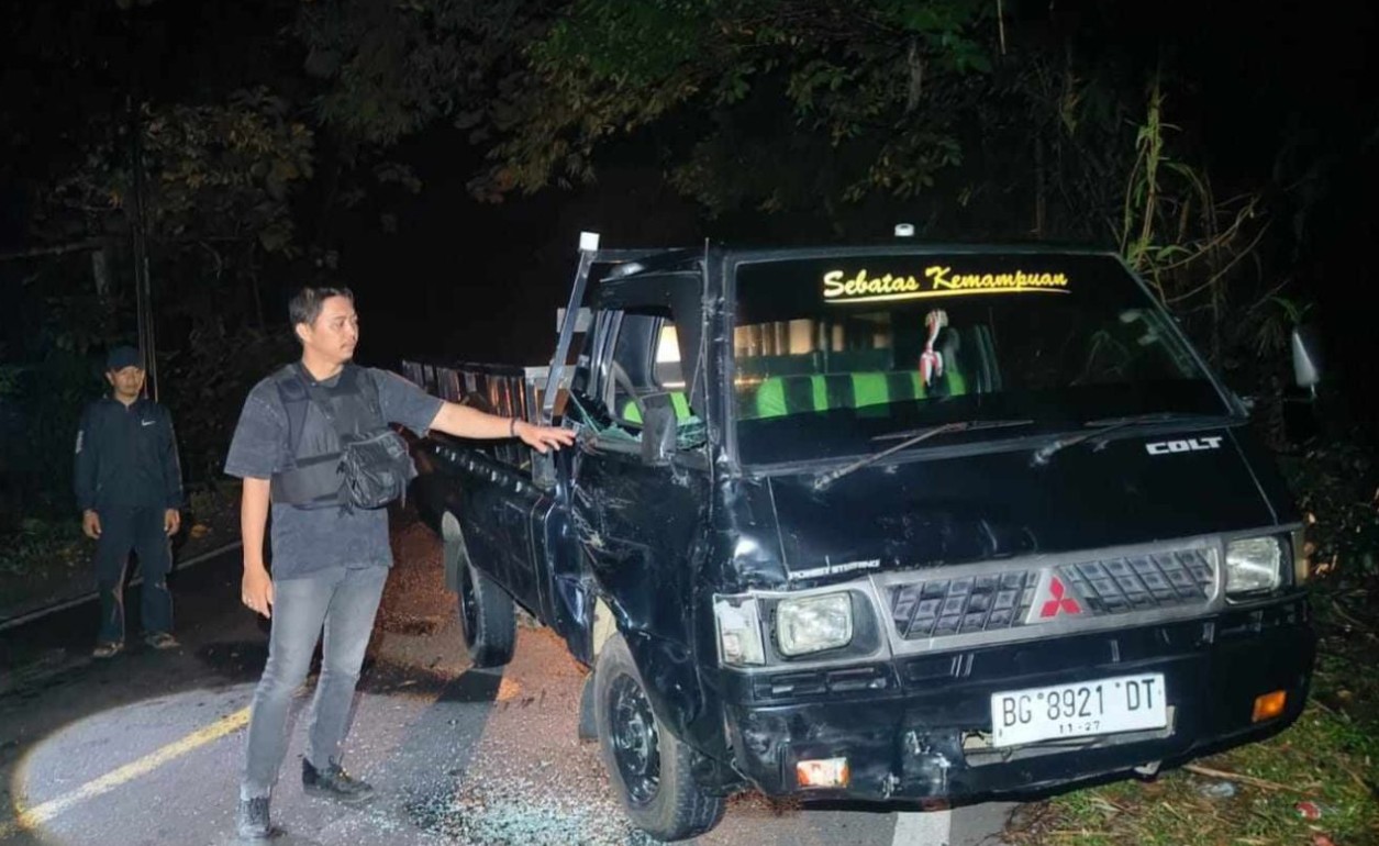 Mobil pick-up rusak parah di bagian depan usai terlibat kecelakaan di jalan raya pada malam hari.