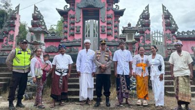 Sebuah foto kelompok yang menunjukkan petugas polisi dan warga Bali berdiri di depan pura Hindu Bali yang besar.