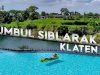 Wisatawan bersantai memakai pelampung kuning di kolam biru Umbul Siblarak Klaten berlatar hamparan sawah