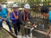 Bupati OKU Teddy Meilwansyah dan Dirut PDAM Bertho Darmo memutar katup pipa air di samping pagar hitam.