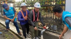 Bupati OKU Teddy Meilwansyah dan Dirut PDAM Bertho Darmo memutar katup pipa air di samping pagar hitam.