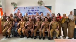 Foto grup besar guru-guru SMPN 19 OKU seragam PNS cokelat duduk dan berdiri di depan spanduk supervisi. Dua pria utama duduk di tengah depan. Beberapa guru membuat isyarat tangan OK.