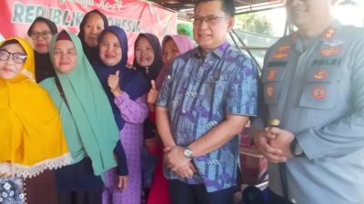 Berpose bersama warga: Wakil Bupati OKU, H. Marjito Bachri, dan Kapolres OKU, AKBP Endro Aribowo, berdiri bersama sekelompok ibu-ibu warga penerima manfaat bantuan banjir di Baturaja Timur.