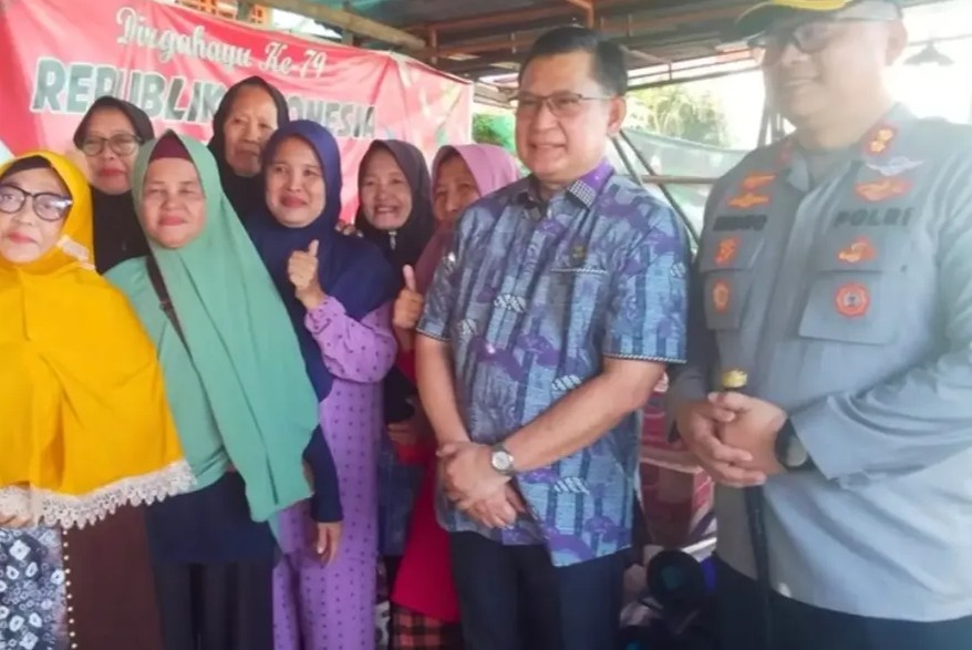 Berpose bersama warga: Wakil Bupati OKU, H. Marjito Bachri, dan Kapolres OKU, AKBP Endro Aribowo, berdiri bersama sekelompok ibu-ibu warga penerima manfaat bantuan banjir di Baturaja Timur.