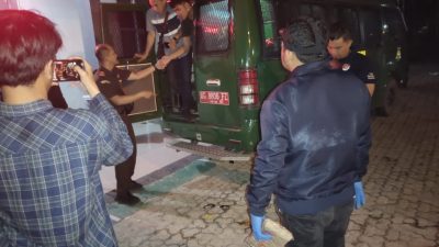 Petugas kepolisian dan jaksa memeriksa mobil tahanan hijau BG 9806 FZ di depan Rutan Baturaja saat malam hari terkait insiden tahanan kabur.