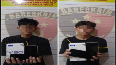 Kolase dua foto pria muda dengan wajah disensor piksel, berdiri di depan spanduk Bareskrim Polsek Baturaja Timur, memegang kotak ponsel putih Vivo Y50 dan dua unit smartphone hitam.