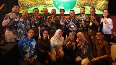 Sekelompok staf Pertamina PEP Zona 4 tersenyum gembira memegang trofi PROPER di panggung penghargaan yang meriah.