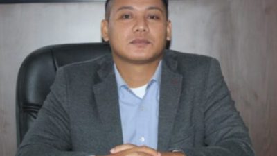Potret Aktivis Kabupaten OKU Ahmad Mubasyir S.P CPLA mengenakan jas abu-abu duduk di meja kerja.