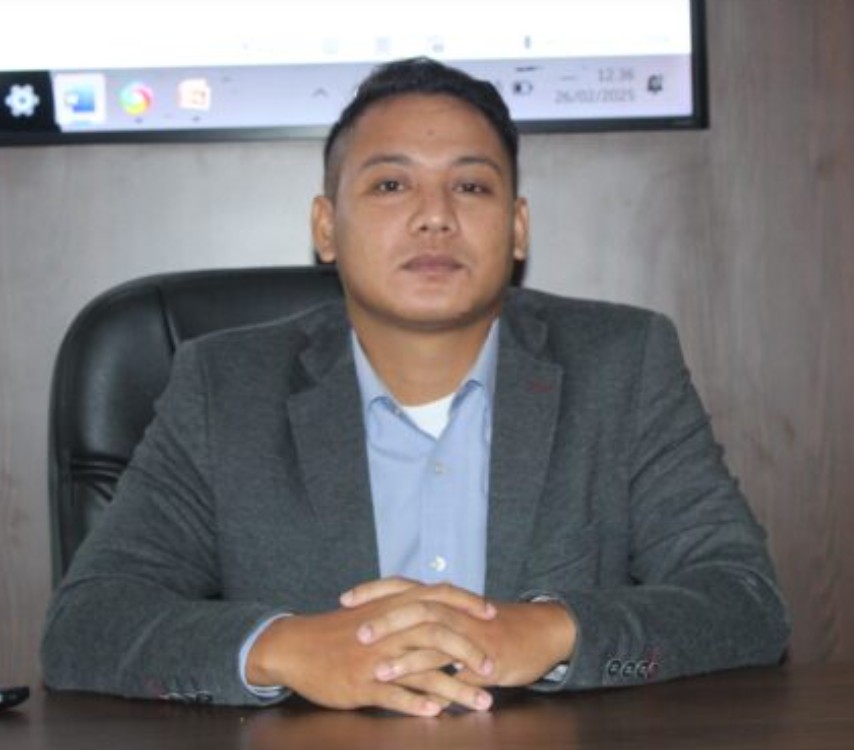 Potret Aktivis Kabupaten OKU Ahmad Mubasyir S.P CPLA mengenakan jas abu-abu duduk di meja kerja.