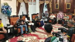 Bupati OKU Teddy Meilwansyah berbaju batik formal duduk memberikan motivasi kepada tim voli muda AVOKU (baju olahraga hijau dan kuning) yang duduk di hadapannya di ruang tamu formal pendopo rumah dinas.