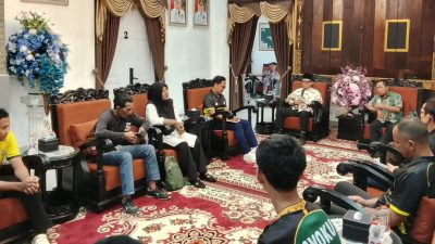 Bupati OKU Teddy Meilwansyah berbaju batik formal duduk memberikan motivasi kepada tim voli muda AVOKU (baju olahraga hijau dan kuning) yang duduk di hadapannya di ruang tamu formal pendopo rumah dinas.