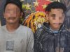 Dua pria muda dengan wajah disensor berdiri berdampingan. Pria di kiri mengenakan kaus abu-abu kotor dengan logo kecil; pria di kanan mengenakan hoodie bermotif hitam-putih dengan grafik tangan di bagian depan. Mereka berdiri di depan spanduk latar belakang pers kepolisian yang menampilkan logo singa.