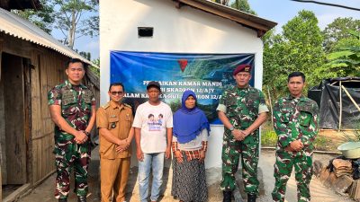 ultah 14 Skadron 12 Amur Jaya Yudha.jpg, adalah foto bersama yang lebih besar yang diambil di depan teras sebuah bangunan (posko atau bangunan fasilitas umum). Sekelompok personel TNI, baik yang berdiri maupun jongkok, bersama beberapa warga sipil, berpose serempak dengan simbol tangan "persatuan" (tangan disilangkan di dada). Di belakang mereka, spanduk besar dan jelas bertuliskan "KARYA BAKTI TNI DALAM RANGKA HUT KE-14 SKADRON 12/AMU JAYA YUDHA". Foto ini menunjukkan semangat kebersamaan dan kekompakan antara TNI dan masyarakat. Bangunan di belakang memiliki atap genteng merah yang khas.