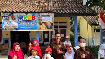 Sekelompok guru dan siswa SD Negeri 183 OKU berpose ceria di depan gedung sekolah yang dihiasi spanduk PPDB dan bendera Merah Putih.