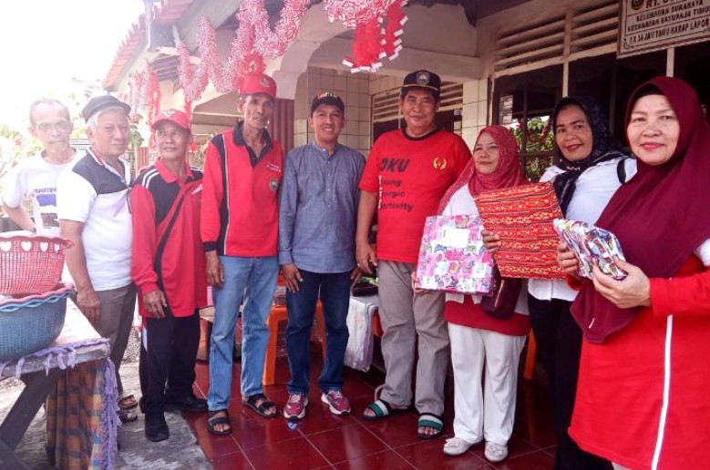 Warga dan pengurus RT 01 RW 03 Kelurahan Sukaraya Baturaja berfoto bersama sambil memegang hadiah kado lomba di teras berhias ornamen merah putih.