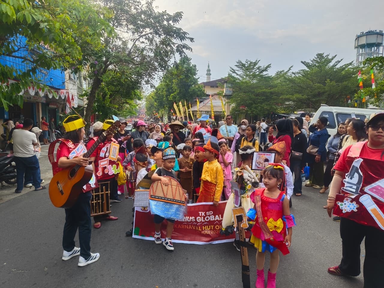 Anak-anak TK SD Xaverius Global School Baturaja memakai kostum unik membawa spanduk karnaval di Jalan Akmal.
