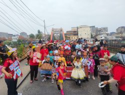 Rombongan pawai TK SD Xaverius Global School mengenakan kostum budaya dan profesi melintasi Jembatan Ogan Baturaja.