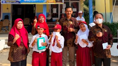 Sekelompok guru dan siswa SD Negeri 183 OKU berpose ceria di depan gedung sekolah yang dihiasi spanduk PPDB dan bendera Merah Putih.