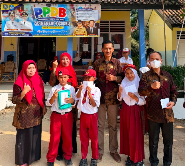 Sekelompok guru dan siswa SD Negeri 183 OKU berpose ceria di depan gedung sekolah yang dihiasi spanduk PPDB dan bendera Merah Putih.