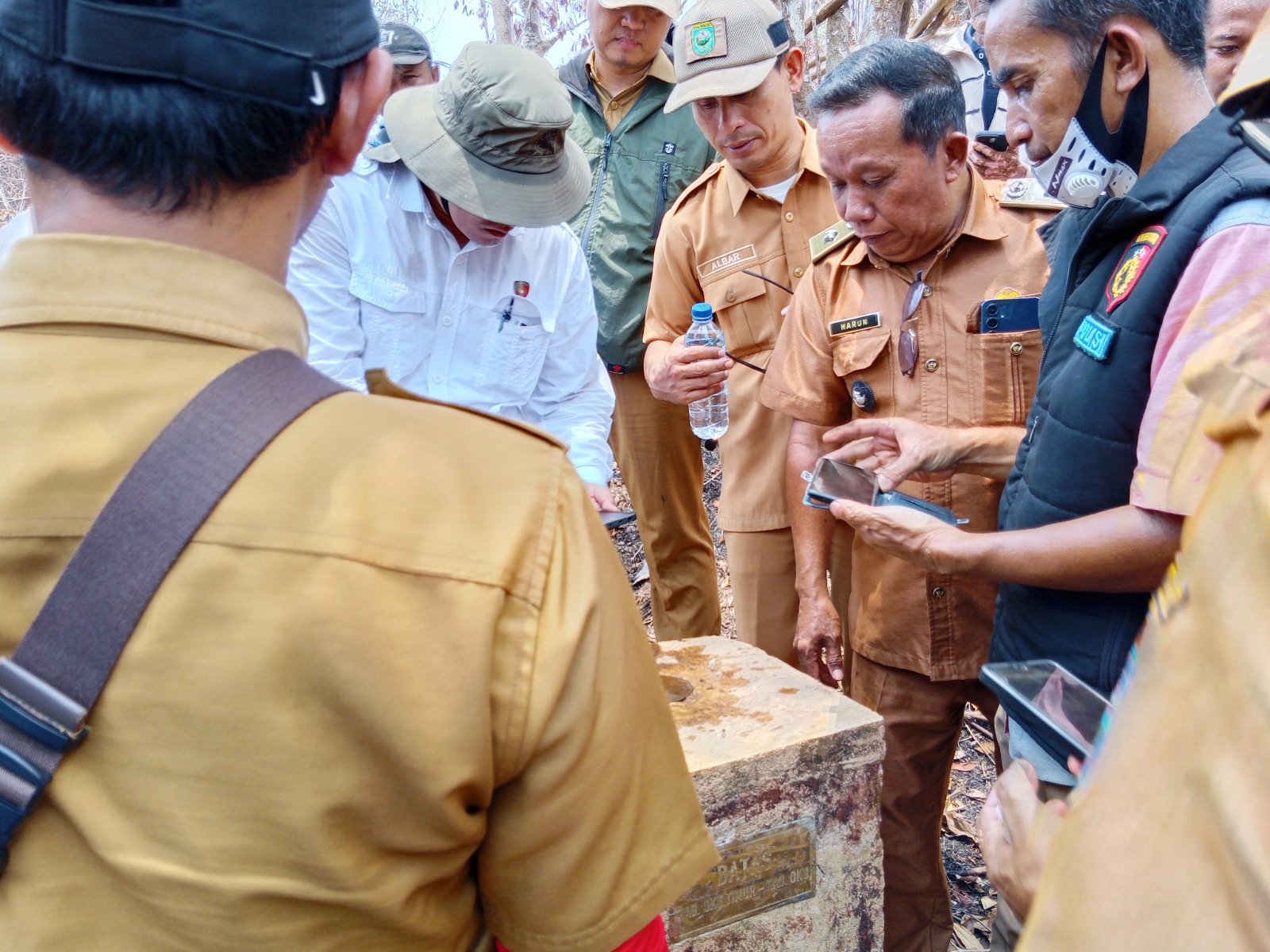 Kades Harun dikelilingi rombongan saat menunjukkan patok beton bertuliskan batas daerah atau PBU 064.jpg