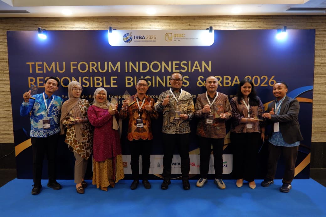 Foto bersama delapan perwakilan PHE OKRT membawa piala penghargaan di depan backdrop acara IRBA 2026.
