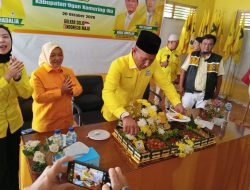 Ketua DPD Golkar OKU Yoni Risdianto sedang memotong nasi tumpeng kuning di atas meja bersama para pengurus partai.