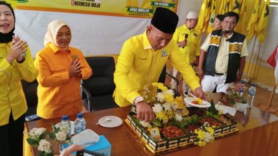 Ketua DPD Golkar OKU Yoni Risdianto sedang memotong nasi tumpeng kuning di atas meja bersama para pengurus partai.