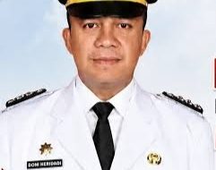 Potret resmi Camat Baturaja Timur, Doni Heridadi, mengenakan seragam dinas upacara berwarna putih lengkap dengan topi jabatan dan dasi hitam.