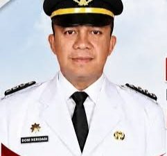 Potret resmi Camat Baturaja Timur, Doni Heridadi, mengenakan seragam dinas upacara berwarna putih lengkap dengan topi jabatan dan dasi hitam.