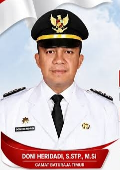 Potret resmi Camat Baturaja Timur, Doni Heridadi, mengenakan seragam dinas upacara berwarna putih lengkap dengan topi jabatan dan dasi hitam.