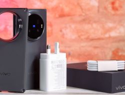 Ponsel pintar lipat Vivo X Fold 6 berwarna hitam dalam posisi berdiri di samping adaptor pengisi daya berwarna putih, gulungan kabel data putih, dan kotak kemasan hitam bertuliskan vivo X Fold6.