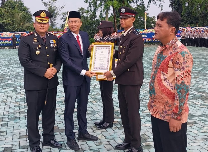 Sekda OKU Alva Elan dan Kapolres OKU AKBP Endro Aribowo menyerahkan piagam penghargaan bertingkai emas kepada seorang anggota kepolisian pada Upacara Hari Bhayangkara ke-80 di Mapolres OKU.
