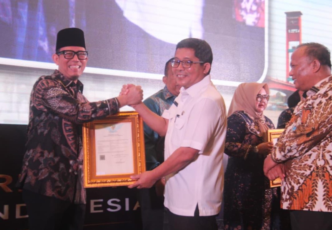 Bupati OKU Teddy Meilwansyah tersenyum saat berjabat tangan dan menerima bingkai sertifikat Kekayaan Intelektual Komunal Tari Nyambai Ugan dari perwakilan Kementerian Hukum RI di Hotel Aryaduta Palembang.