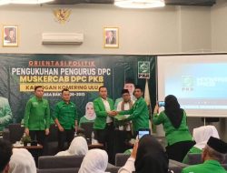 Kader Partai Kebangkitan Bangsa berseragam hijau saling menyerahkan dokumen di atas panggung dengan latar spanduk Muskercab DPC PKB Kabupaten OKU.