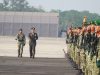 Inspektur upacara militer berjalan memeriksa barisan prajurit TNI bersenjata.