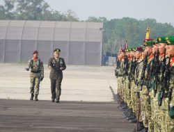 Inspektur upacara militer berjalan memeriksa barisan prajurit TNI bersenjata.